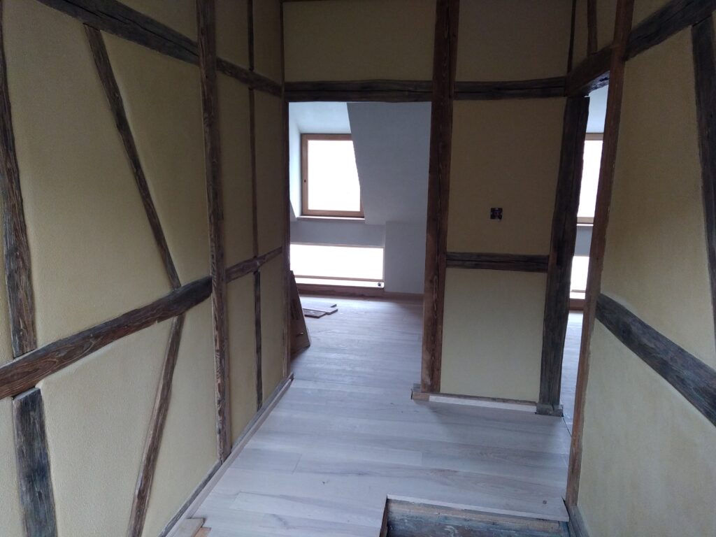 Pièce rénovée avec murs finis à l'enduit naturel sur panneau de roseau, structure bois apparente.