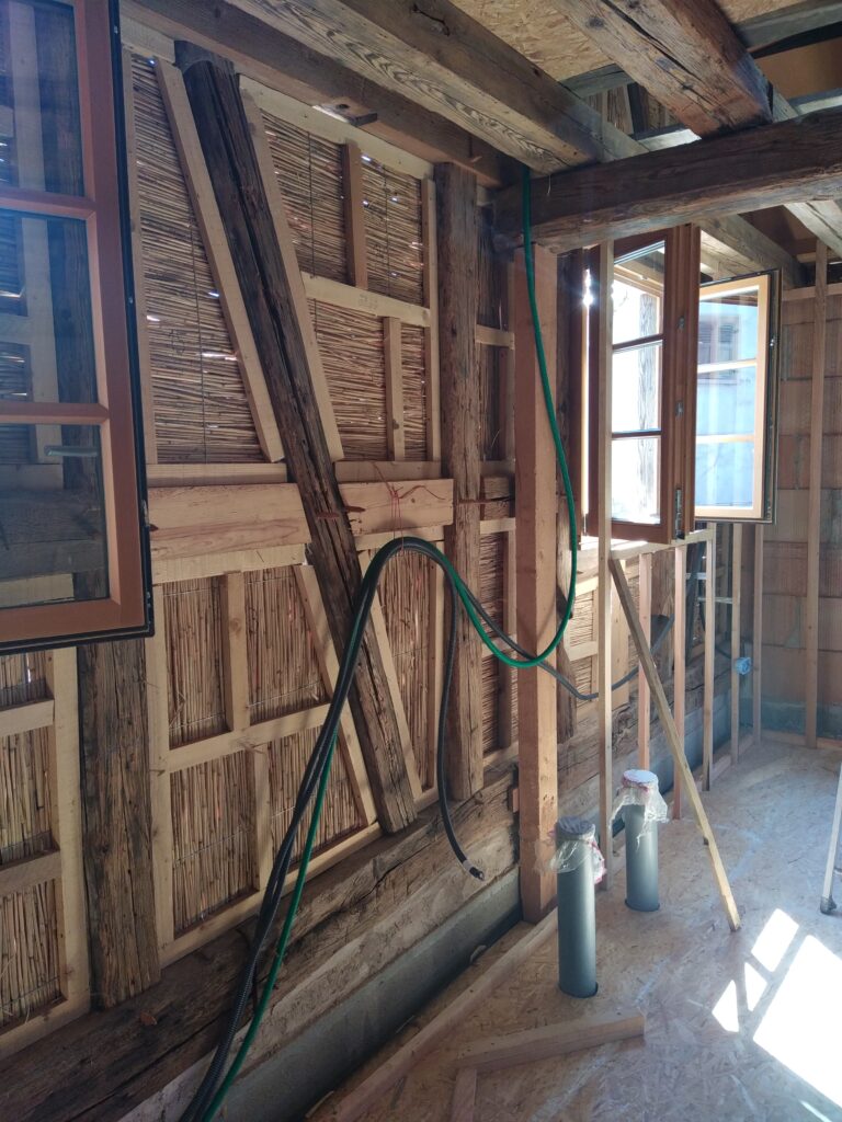 Vue intérieure d'une ossature bois avec panneaux de roseau utilisés en coffrage perdu dans une rénovation de maison à colombages